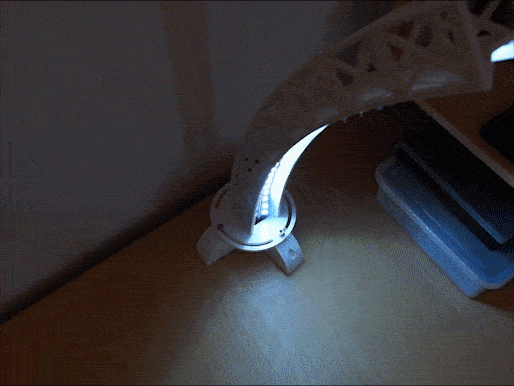 An animation of a rotating desk lamp being rotated back and forth by a hand.