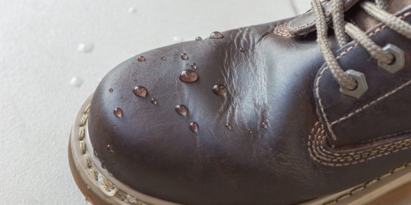 A close-up of water droplets on top of a waterproofed leather shoe.