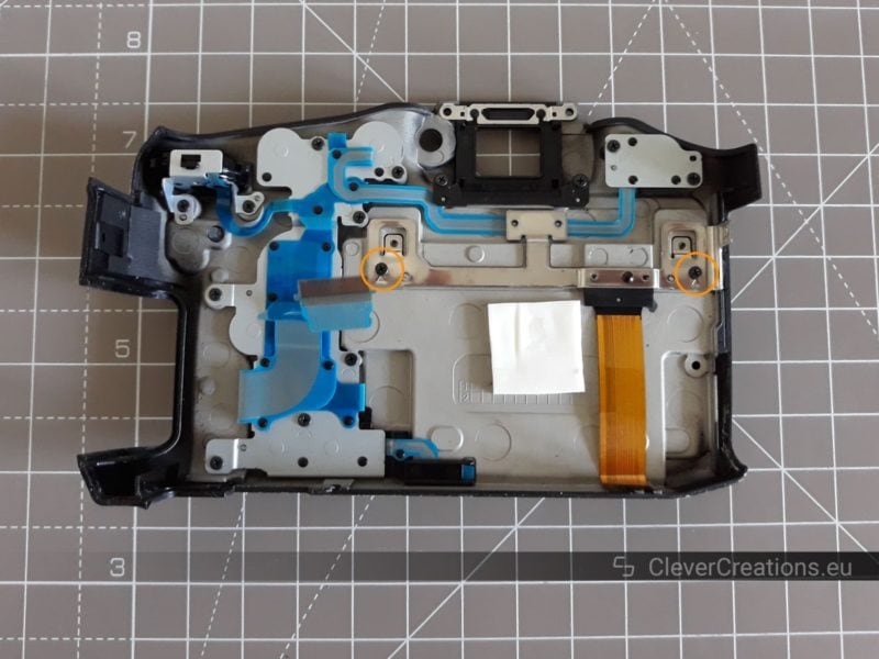 The inside of the rear cover of a Sony SLT-A77 camera. Two exposed screws are circled.