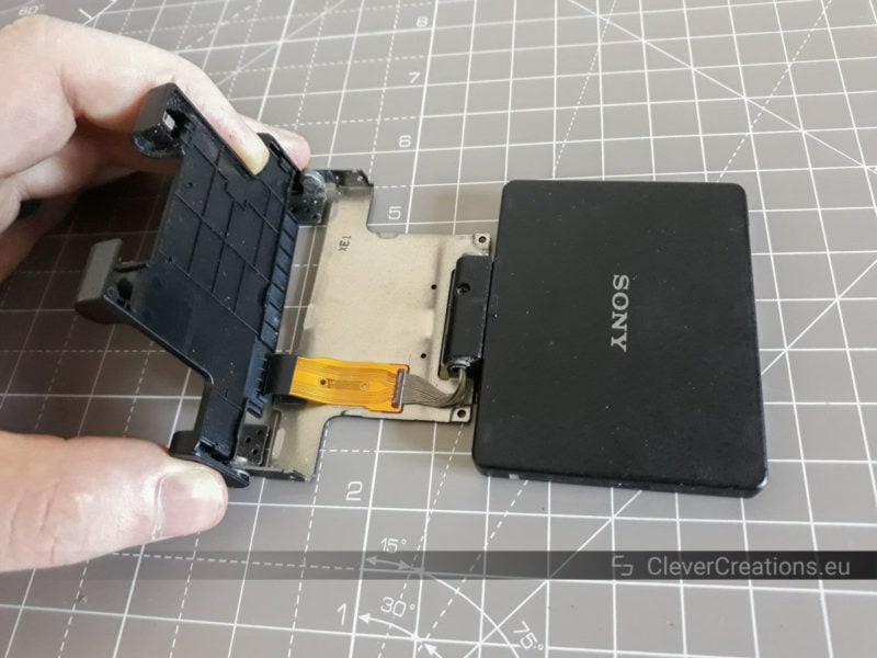 A hand taking the plastic cover off of a DSLR LCD assembly.