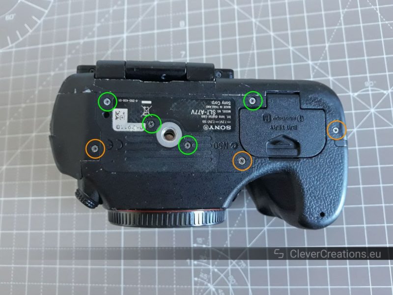 The bottom of a Sony SLT-A77 camera body. Seven exposed screws are circled.