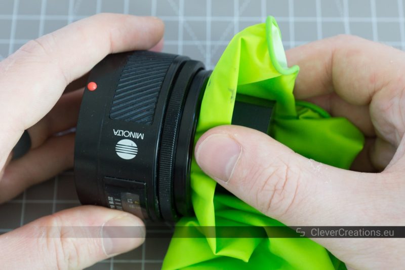 A hand holding a Sony 50mm lens while another hand holds a 3D printed tool against the lens.