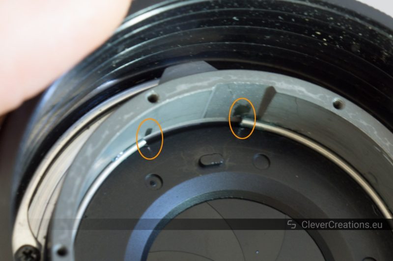 The inside of a camera lens, with two circles around the end points of a circular retainer spring.