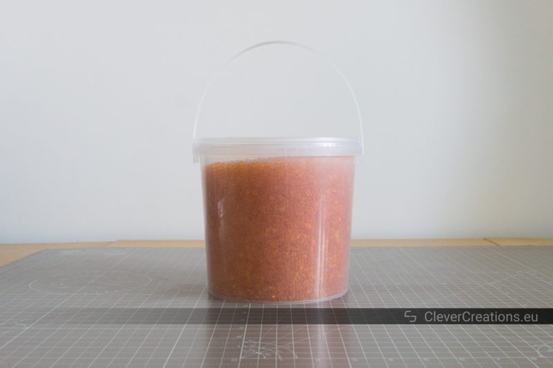 A transparent container with 1 kg of reusable orange silica gel beads that can be used to keep 3D printer filament dry.