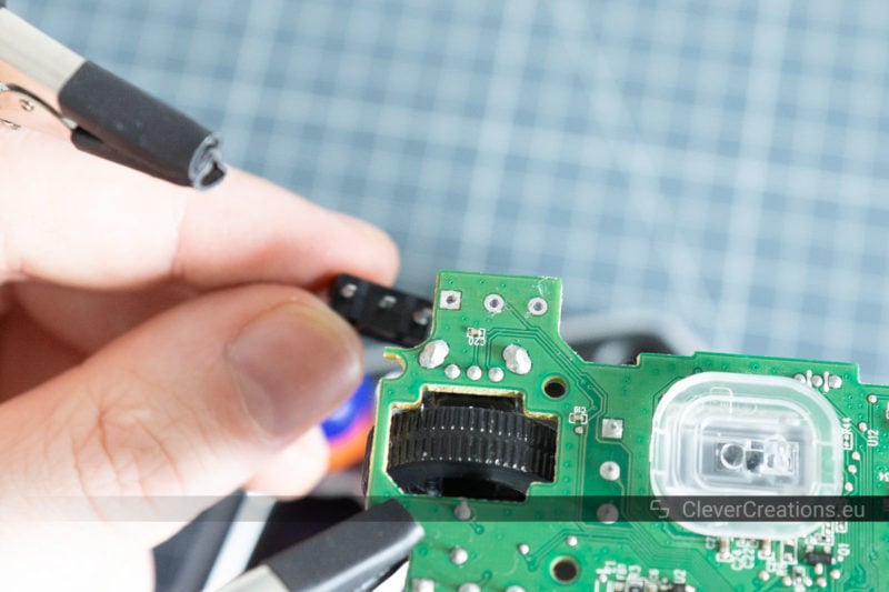 A hand removing a D2FC-F-7N from a mouse PCB.