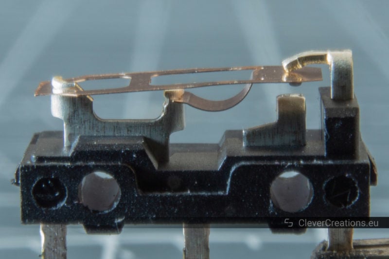 A D2FC–F–7N microswitch without its top cover, with the copper spring visible.