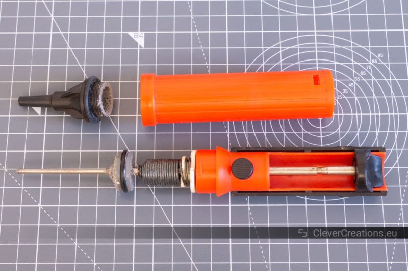Top view of a partially disassembled red desoldering pump (solder sucker).