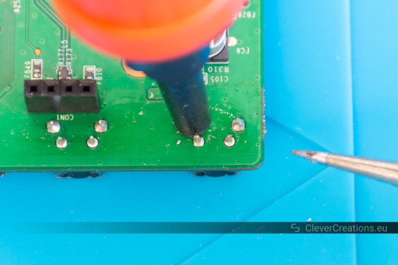 A desoldering pump sucking solder from a circuit board.