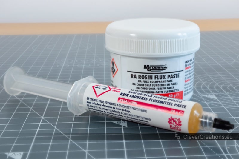 A container with rosin flux with in front of it a syringe with no-clean flux.