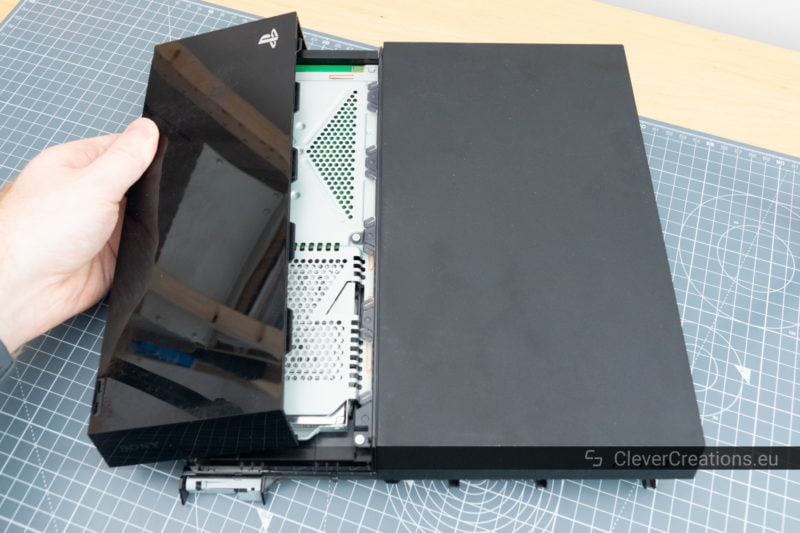 The plastic HDD cover of a PS4 being removed.