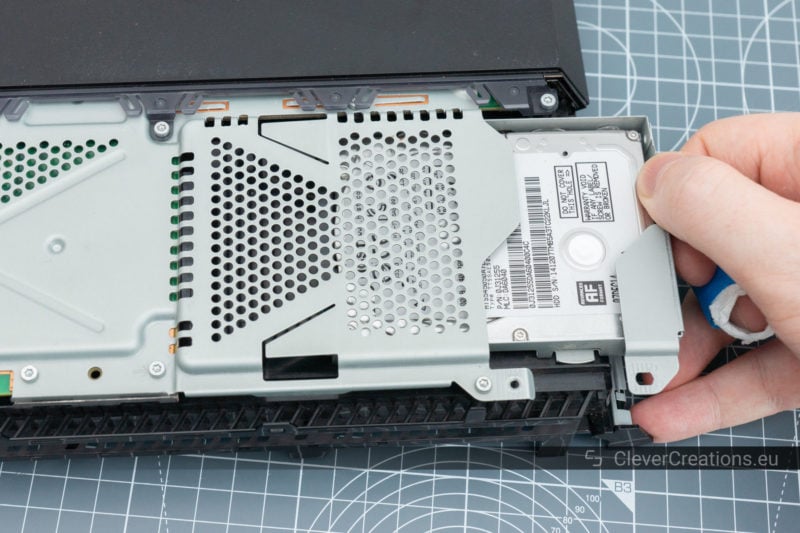 A hand pulling a HDD mount out of a Playstation.