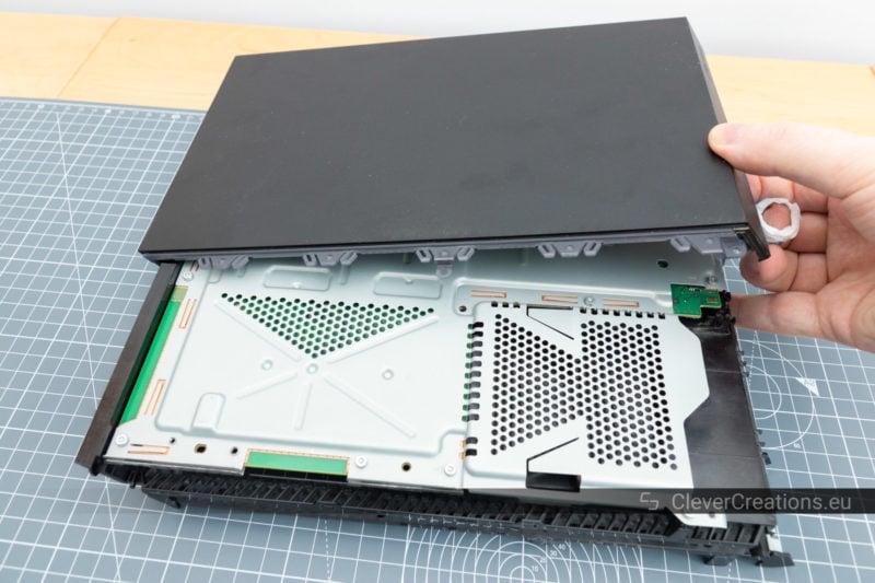 One of the top plastic covers of a Playstation 4 being removed.