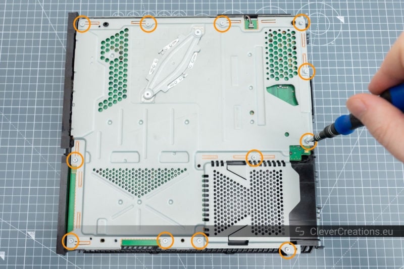Twelve circled screws on the shielding of a Playstation 4 that need to be removed.