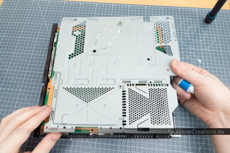 Two hands lifting the shielding of a Playstation 4 out of the console.
