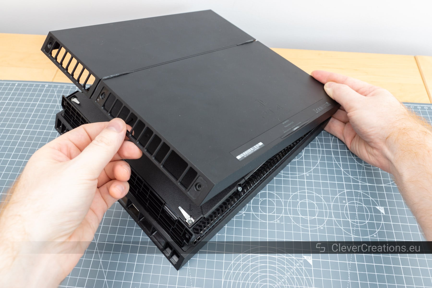 The screws that hold the PS4 power supply in place removed and placed on top of a cutting mat.