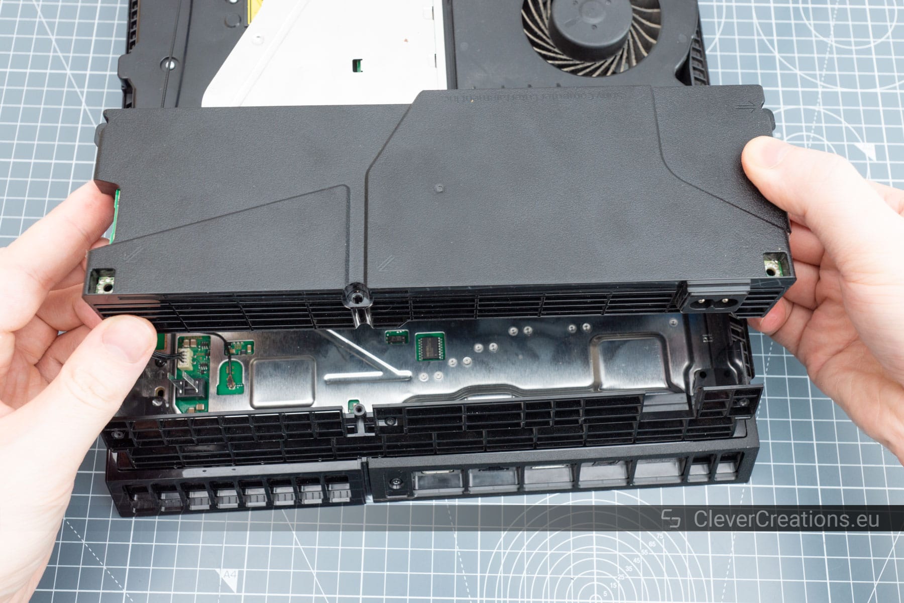 A hand pulling a HDD mount out of a Playstation.