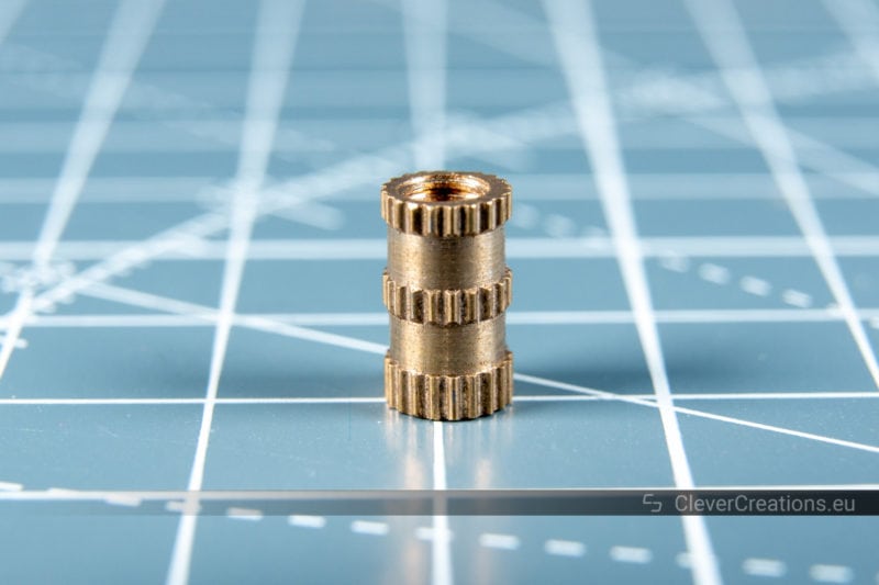 A close-up of a brass threaded insert with straight knurling.