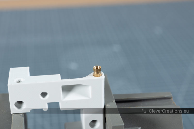 A close-up of a threaded insert placed on the hole of a 3D printed component.