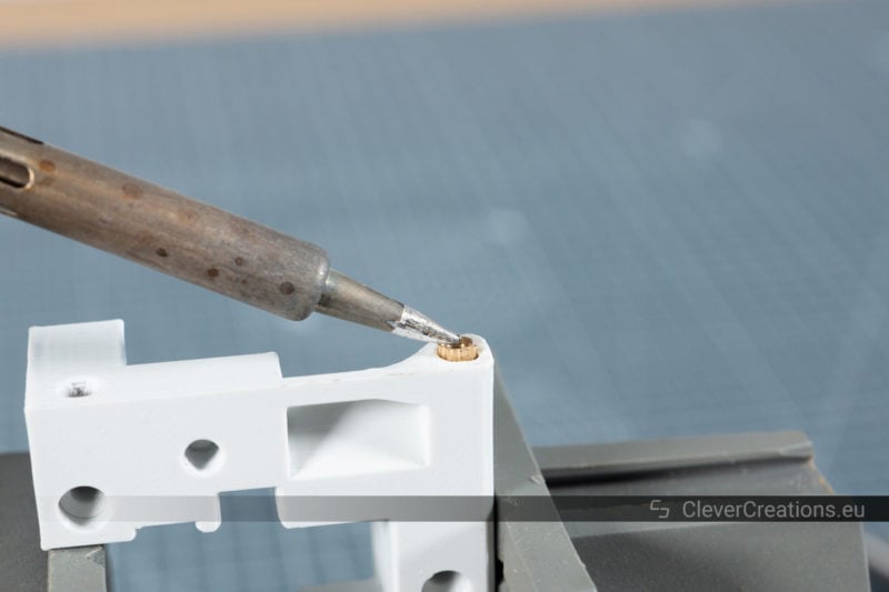 A soldering iron being used to install a threaded insert in a plastic part.