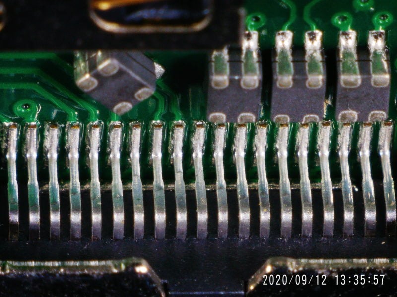 A long row of pins on a PCB, seen at an angle and upside down.
