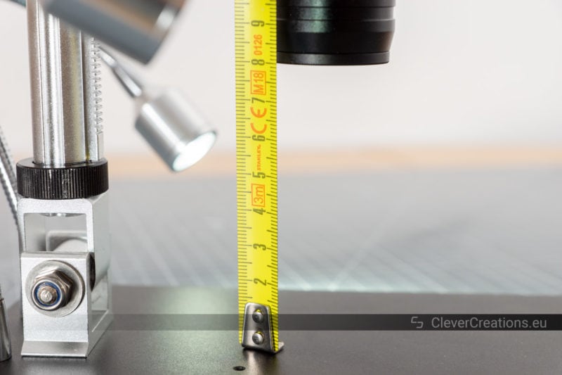 A ruler held next to the lens of a microscope to indicate the maximum vertical working distance.