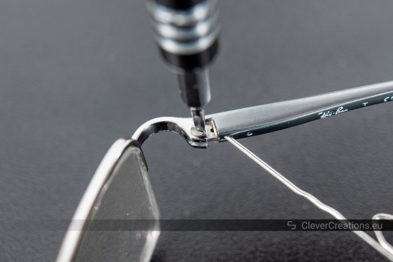 A precision screwdriver driving a screw in a glasses hinge