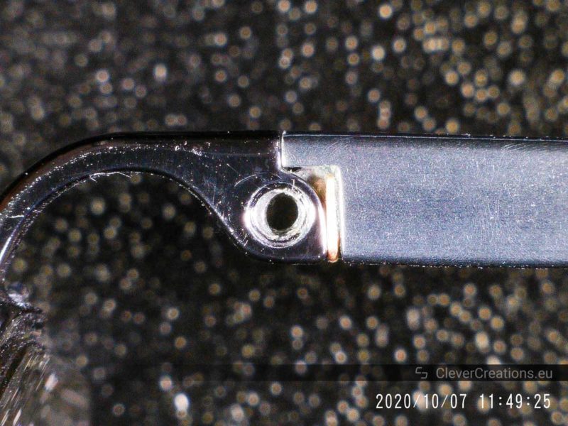 A close-up of misaligned holes on a spring hinge.