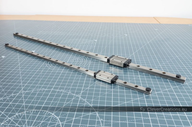 A MGN9 and MGN12 linear guide rail placed next to eachother on a grey cutting mat.