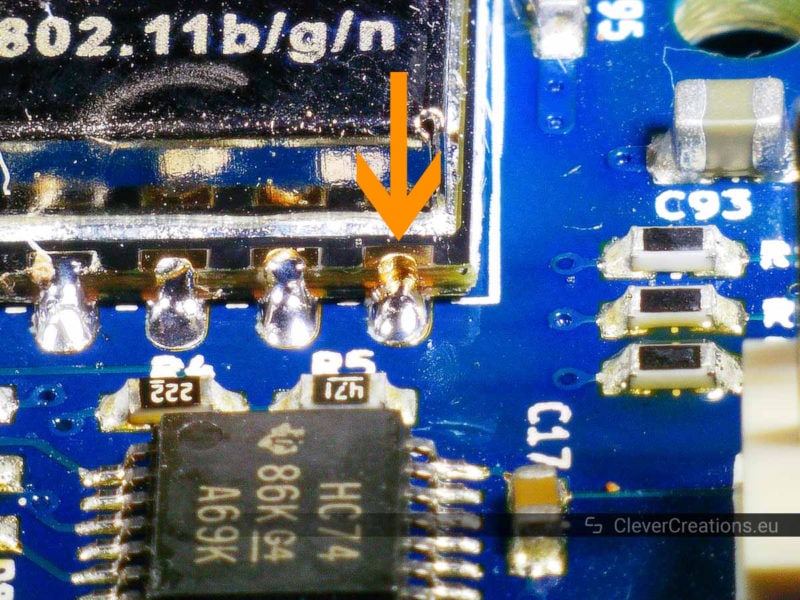 An orange arrow pointing to a faulty solder joint on an ESP-12S Wifi module.