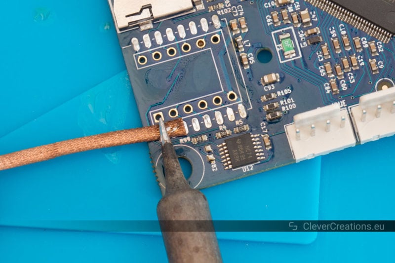 Solder wick and a soldering iron being used to drag away leftover solder from a circuit board.