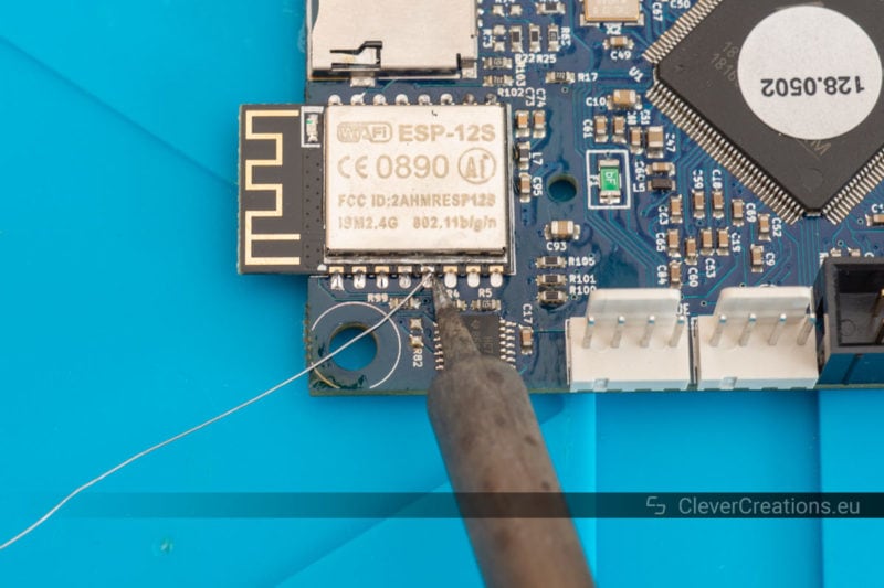 A soldering iron being used to solder the pins of an ESP8266-based wireless module onto a Duet 2 Wifi..