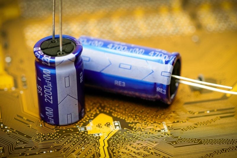 Two aluminum electrolytic capacitors with their negative cathode side facing towards the camera.