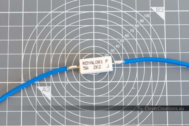 A 5W 2.2kOhm resistor with two blue wires attached to it.