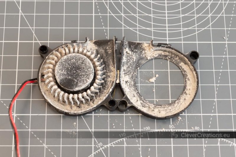 A partially disassembled blower fan that has been completely ruined by dust.