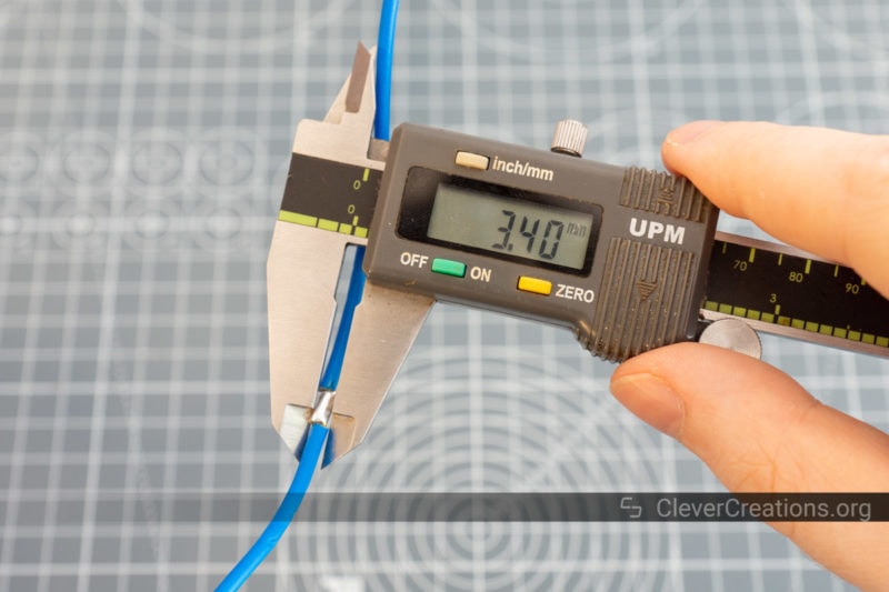 A pair of digital calipers measuring the diameter of a blue wire and reading 3.40mm.