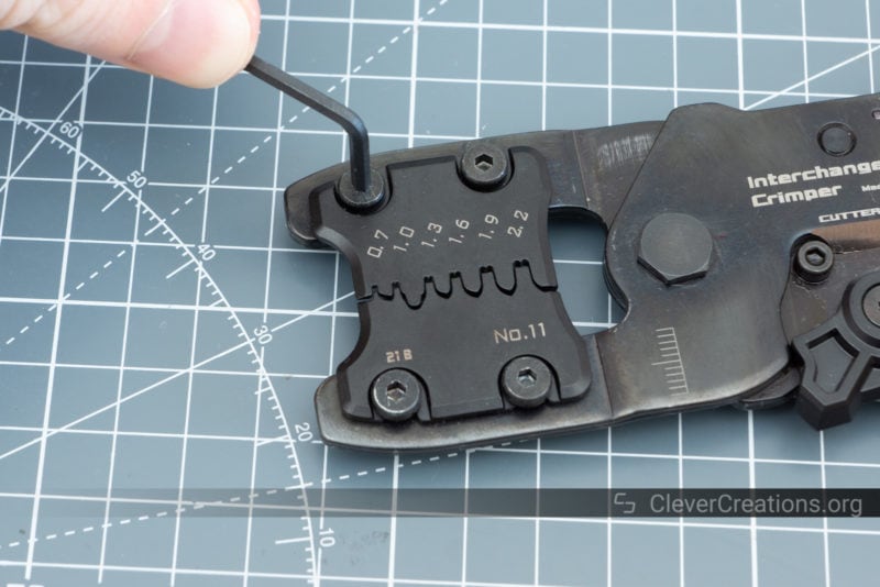A hand using an Allen key to swap the dies of a crimp tool with interchangeable die plates.