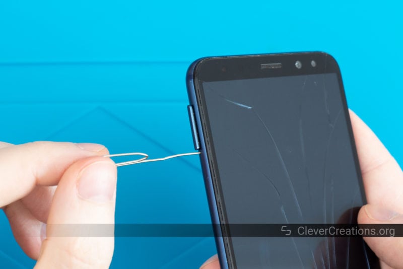 A paperclip being used to eject the SIM/SD card drawer of a Huawei phone.