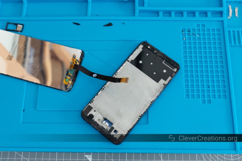 Various components of a phone that is being fixed on a repair mat.