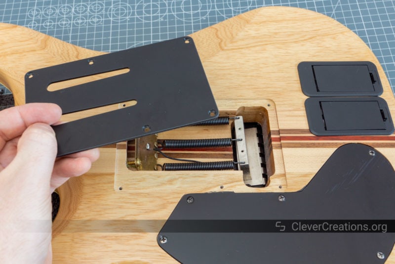 A hand lifting out the backplate of a guitar.