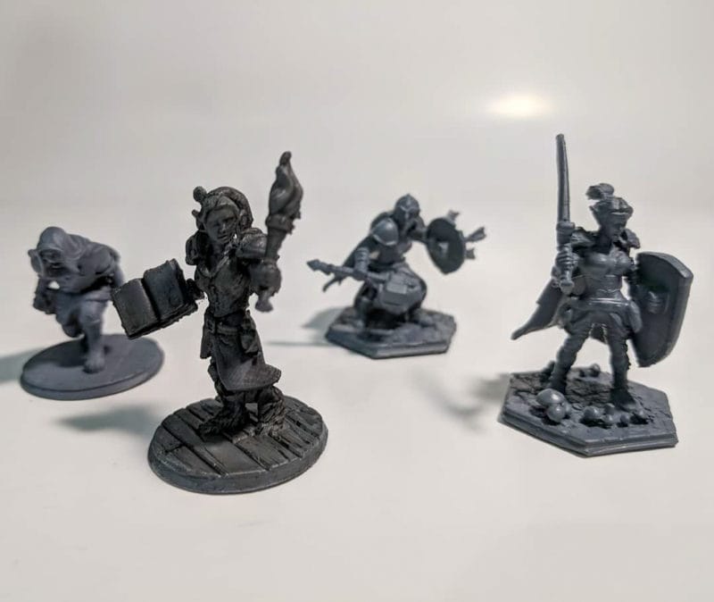 A collection of black Hero Force minis that were 3D printed on a FDM machine