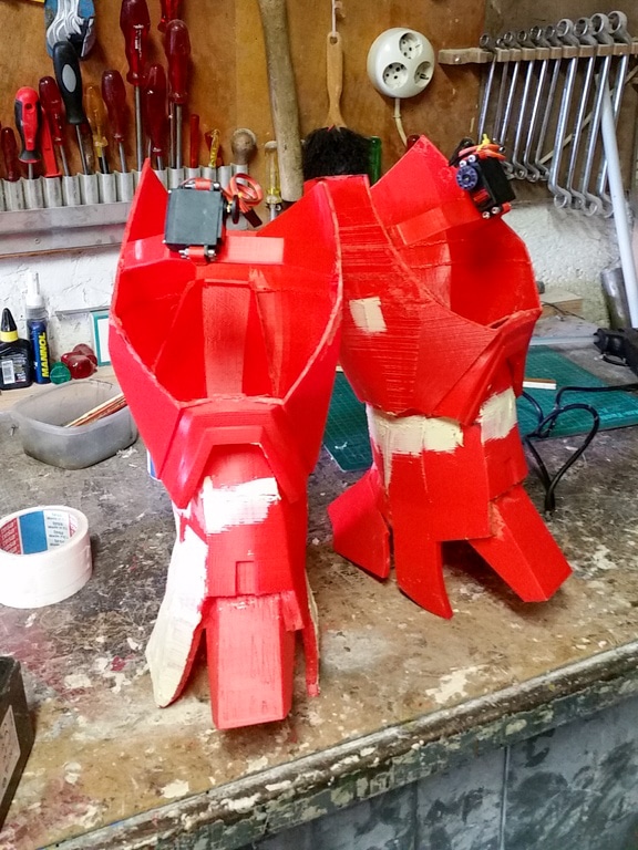 Two red 3D printed pieces of a cosplay costume in post processing stage.