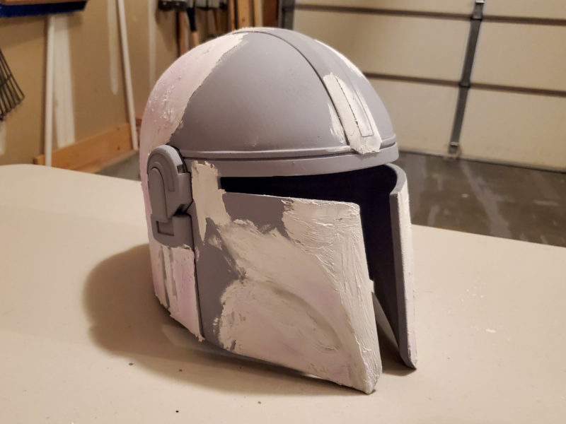 A grey 3D printed helmet with putty applied to it before sanding.