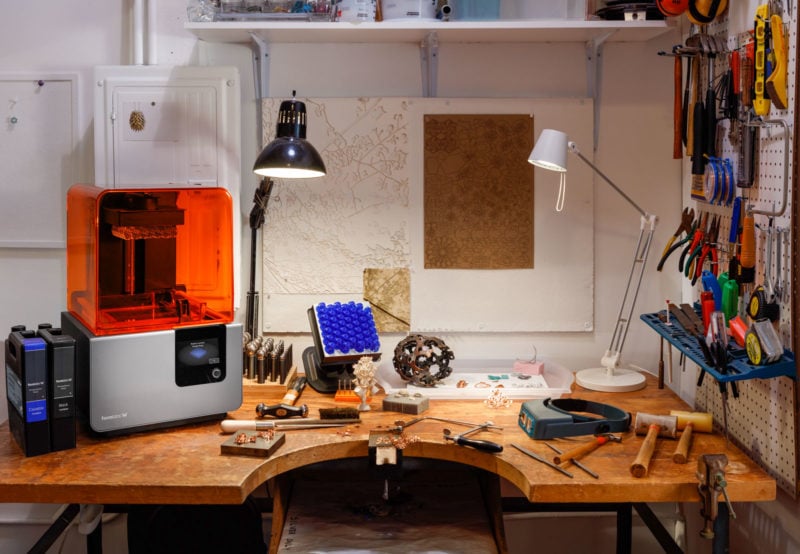 A small hobbyist workshop with a stereolithography 3D printer on a desk