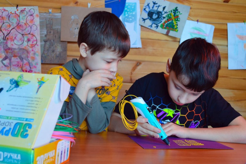 Two children using a 3D pen