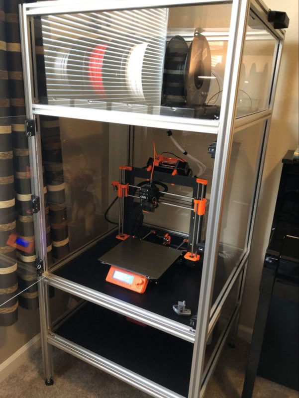 An aluminum extrusion enclosure with a Prusa 3D printer in it.