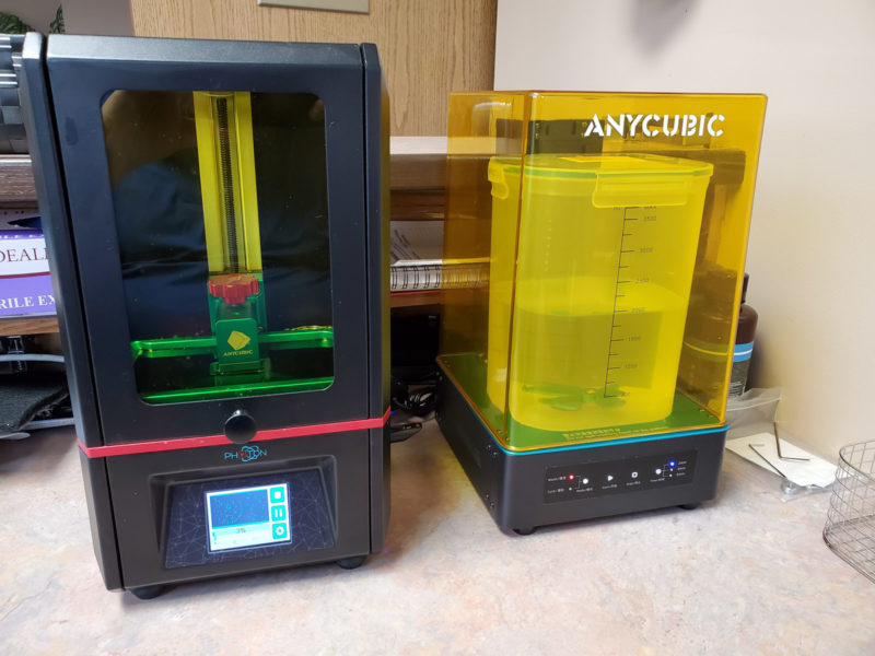 An Anycubic wash and cure accessory next to a resin 3D printer