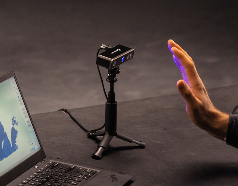 A blue light 3D scanner scanning a human hand.