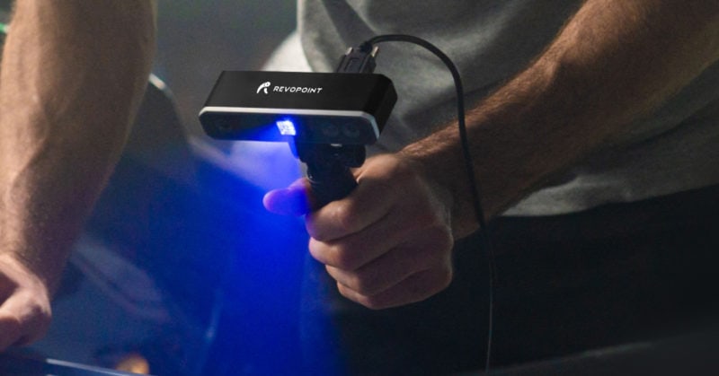 A hand holding a Revopoint MINI scanner