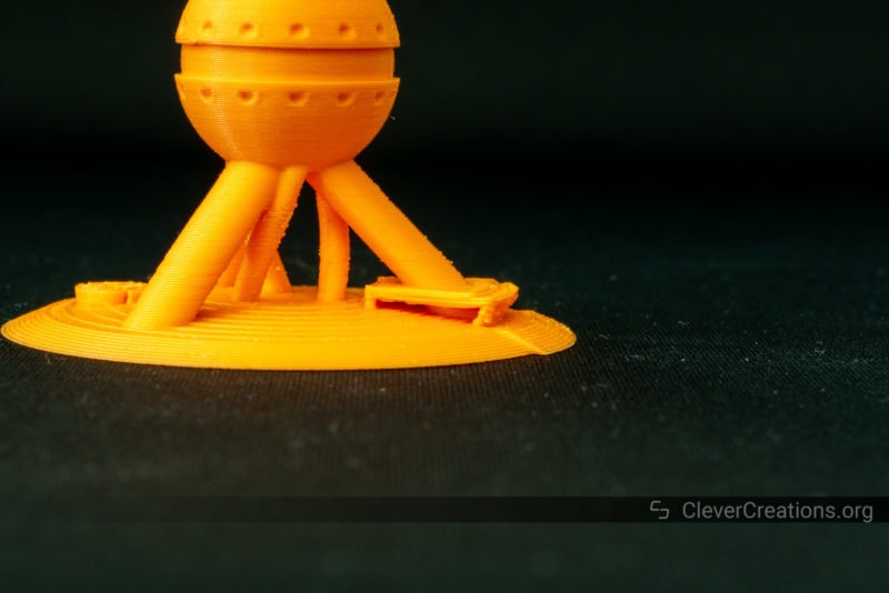 A close-up of overhang details on an orange 3D printed calibration tower