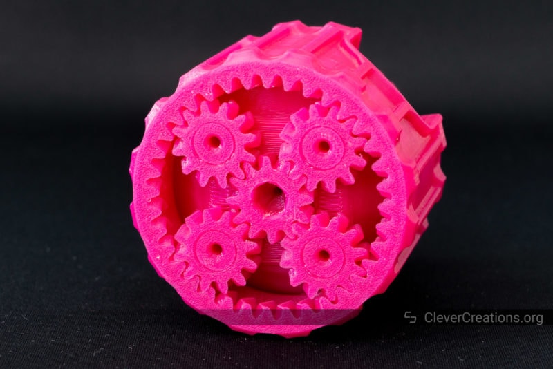 Pink planetary gears on the underside of a 3D printed container